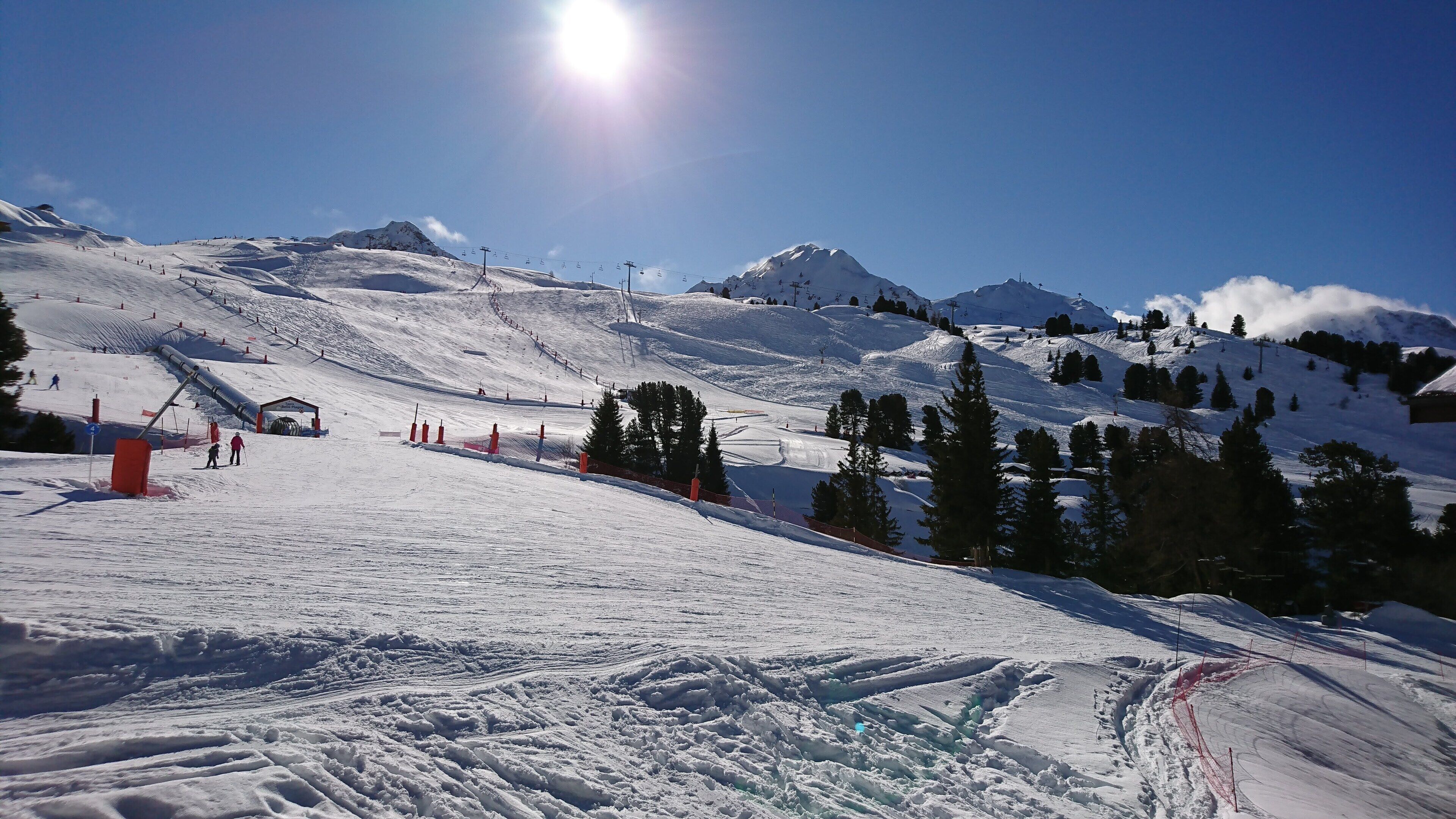 A snowy ski slope with ski lifts and trees.