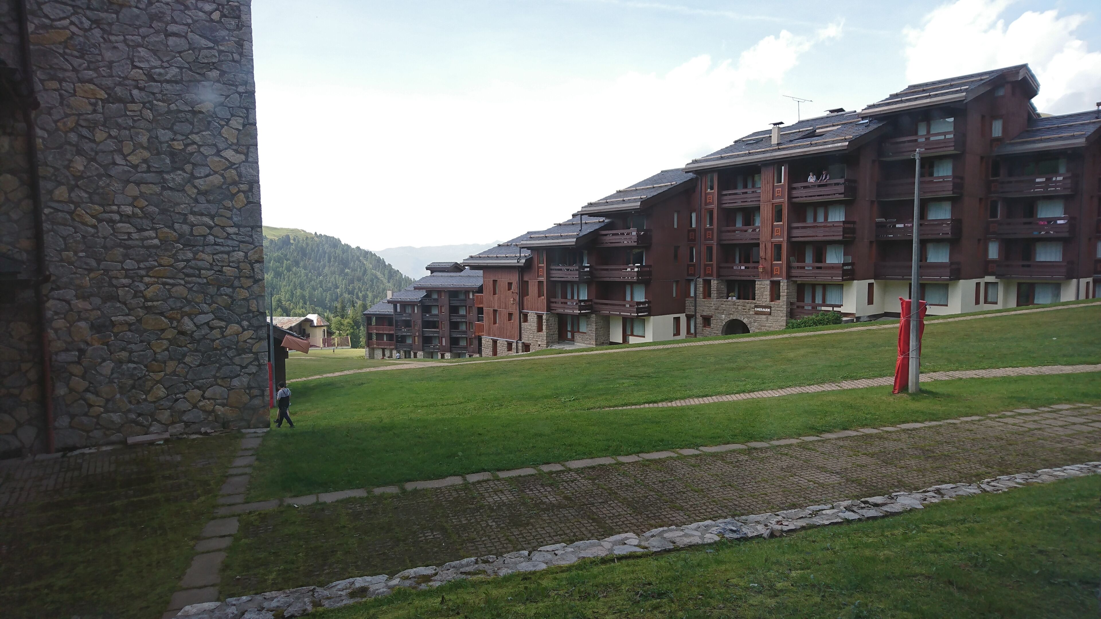 A modern building with multiple balconies and a stone wall.