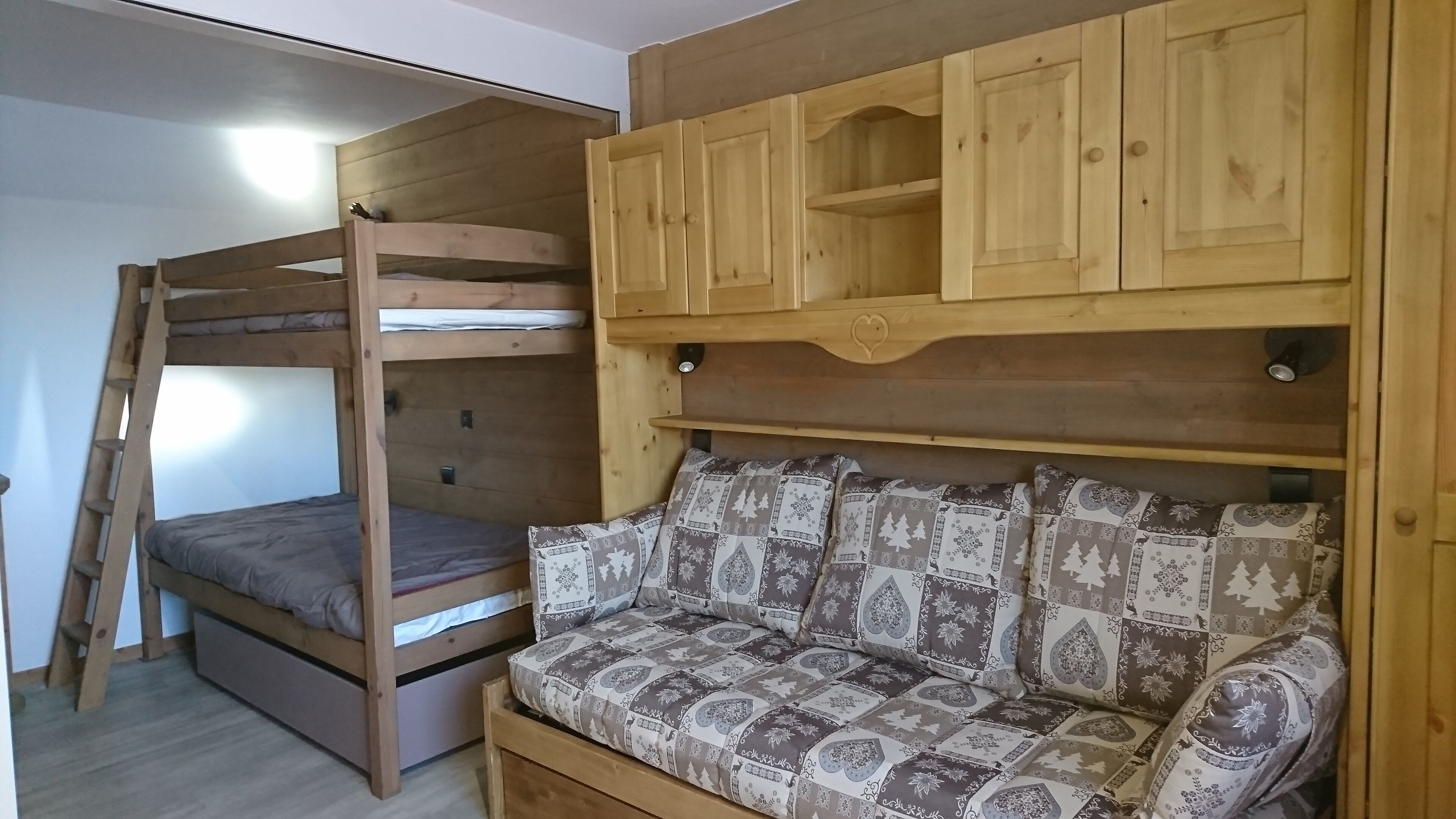 Un letto a castello con un letto inferiore e un divano letto con cuscini decorati.