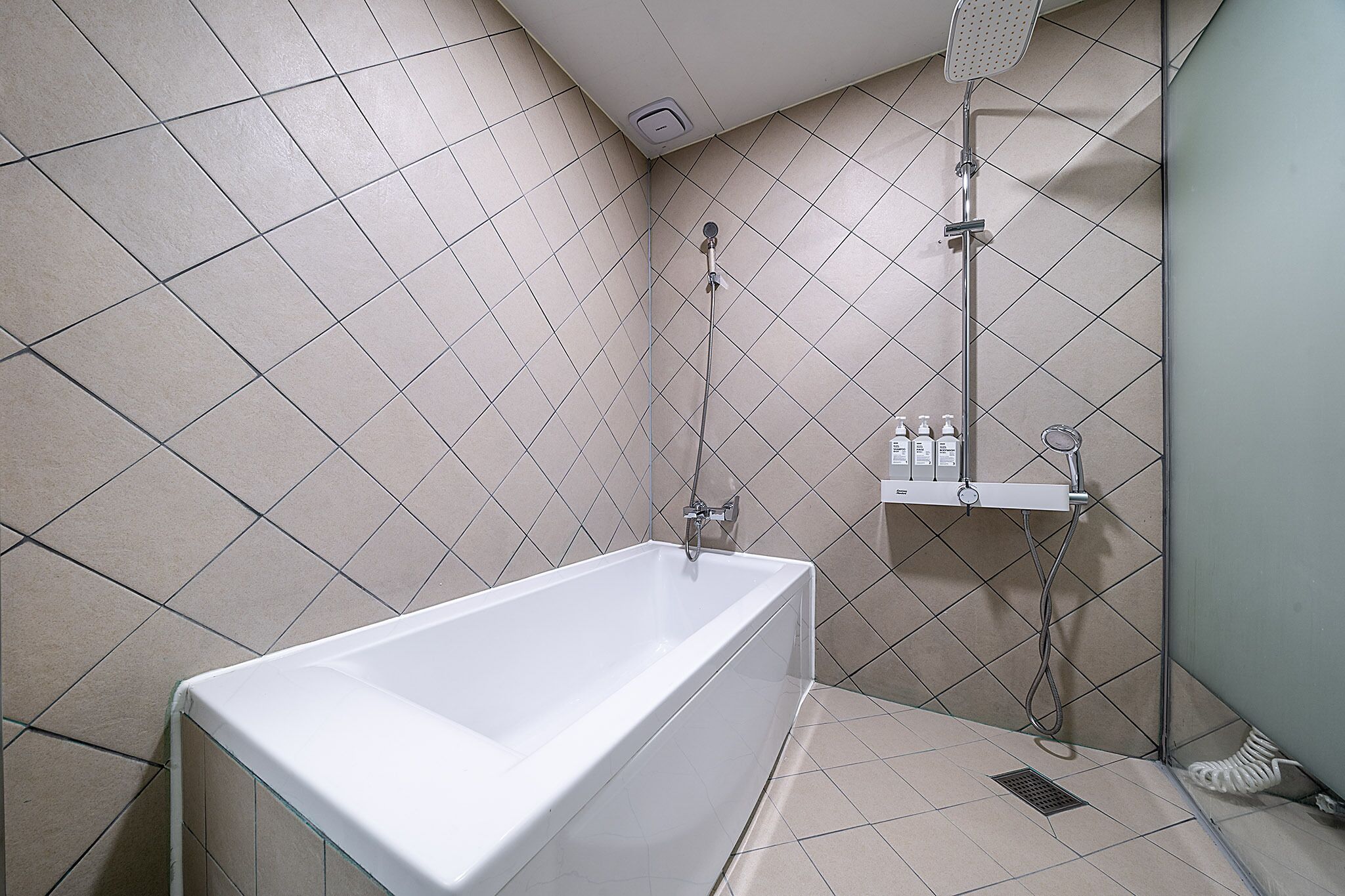 A bathroom with a bathtub, a shower, and a hand dryer.