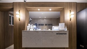 A reception desk with a sign reading "BROWN - DOT HOTEL" and an information board.