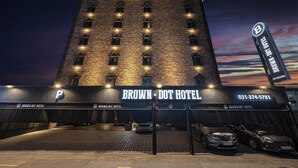 The Brown-Dot Hotel with a prominent 'P' sign indicating parking, a large illuminated sign, and a view of the sky at dusk.
