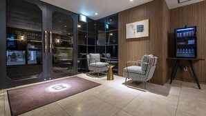 A modern lobby with checkered chairs, a vending machine, and a framed picture on the wall.