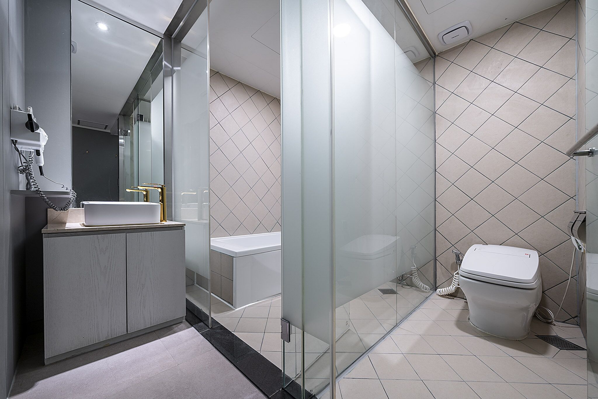 Une salle de bain moderne avec une douche à parois de verre, des toilettes blanches et un meuble-lavabo avec un robinet doré.