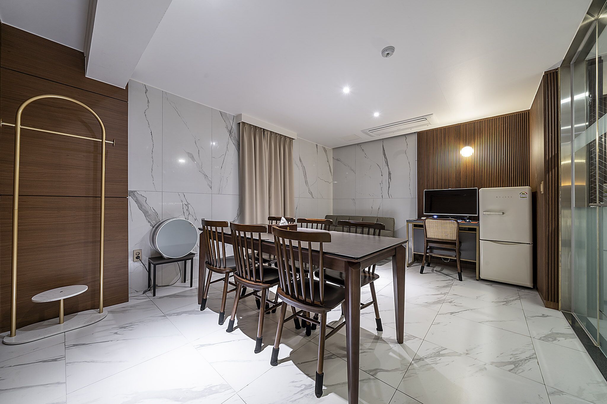 A modern kitchen with a dining area, featuring a marble-tiled floor, wooden furniture, and built-in appliances.
