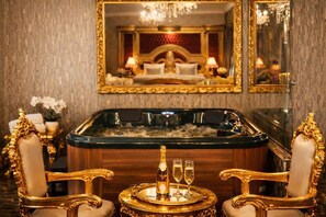A luxurious room with a large bathtub, two ornate chairs, a mirror, and a chandelier. - Prezident Palace Belgrade - Rooftop Pool & Spa Hotel (Belgrade)