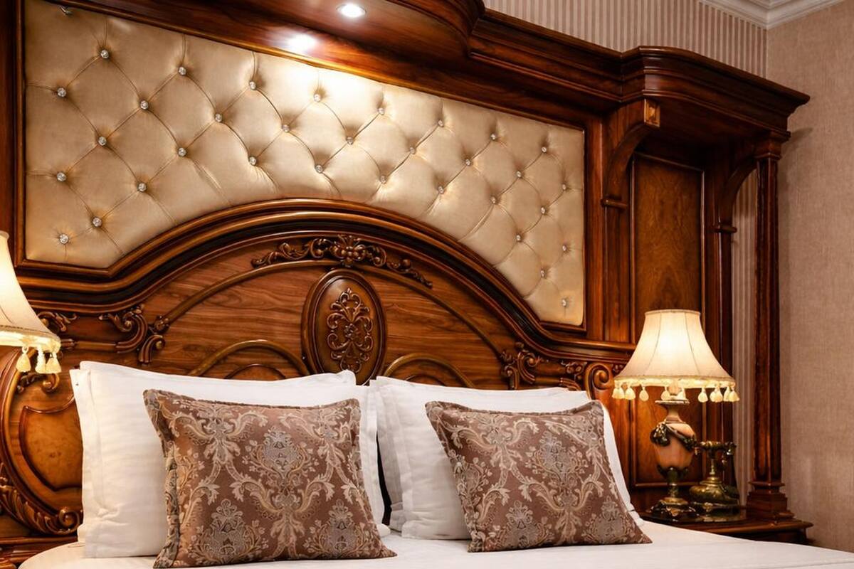 A bed with a tufted headboard, two bedside lamps, and patterned pillows.