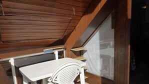 A small, enclosed balcony with a wooden ceiling, a white table, and a white chair. - Cozy 2-room apartment for 4 pers with pets and parking (Les Contamines-Montjoie)