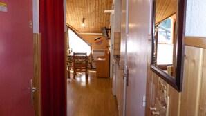 A narrow hallway with wooden walls and a red curtain on the left. A wooden door with a bear decoration is on the right. - Cozy 2-room apartment for 4 pers with pets and parking (Les Contamines-Montjoie)