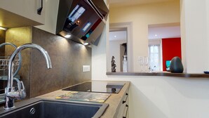 Una cocina moderna con un lavamanos de acero inoxidable, horno empotrado y un televisor de pantalla plana sobre la encimera.