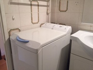 A front-loading washing machine in a bathroom with a white sink and tiled walls. - Charming 2-room, 5 beds at the foot of the slopes, Risoul 1850 (Risoul)