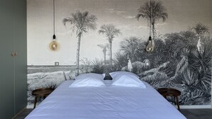 A bedroom with a bed, two bedside tables, a wall mural, and two hanging light fixtures. - Villas Agosta - Acantha - sea view 50 m from the beach, new and luxurious (PIETROSELLA)