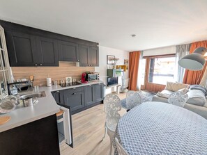 A compact living space with a kitchenette, a dining area, and a sofa.
