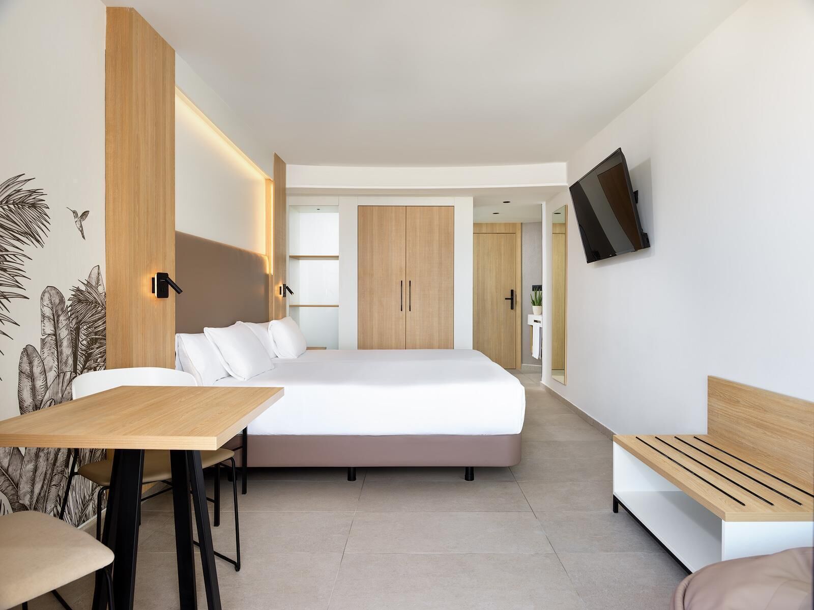 A modern bedroom with a bed, bedside table, and a desk with chairs.