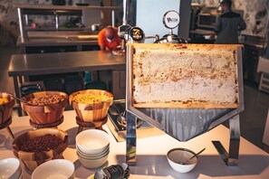 Un buffet proposant divers plats présentés dans des bols en bois, une machine à café et un panneau affichant le menu.