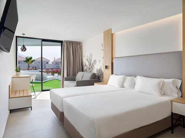 A modern hotel room with a large bed, a desk, a chair, and a view of the outside.