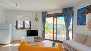 A living room with a TV, sofa, and yellow chair. - Holiday Home Ira with pool, family friendly, WiFi, parking, pets allowed (Krk)