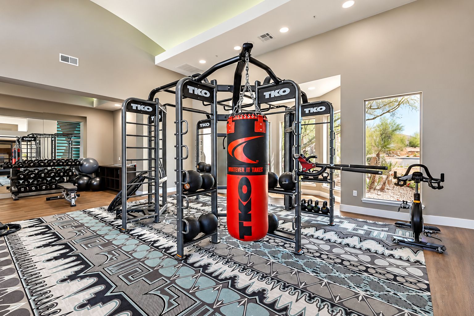Ein Fitnessstudio mit einem TKO-Sack, Gewichte und einem Ergometer.
