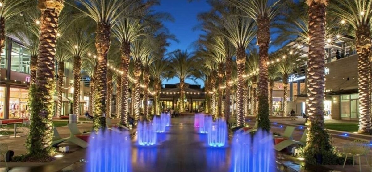 A well-lit outdoor area with palm trees and a water feature.