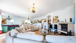 Ein geräumiges Wohnzimmer mit einer großen Couch, einem Kamin und Kunstwerken an den Wänden.