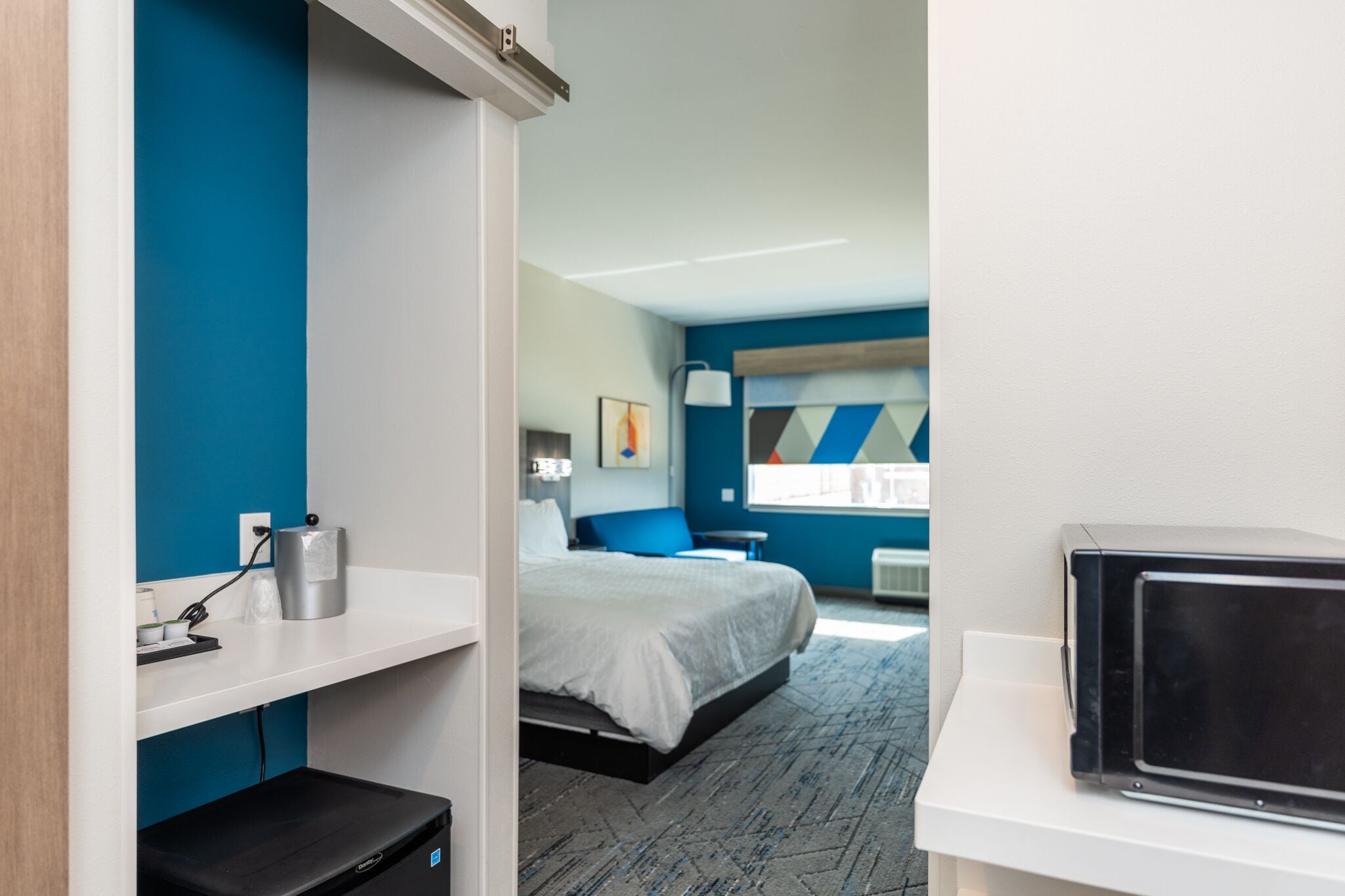 A modern hotel room with a bed, a desk, and a television.