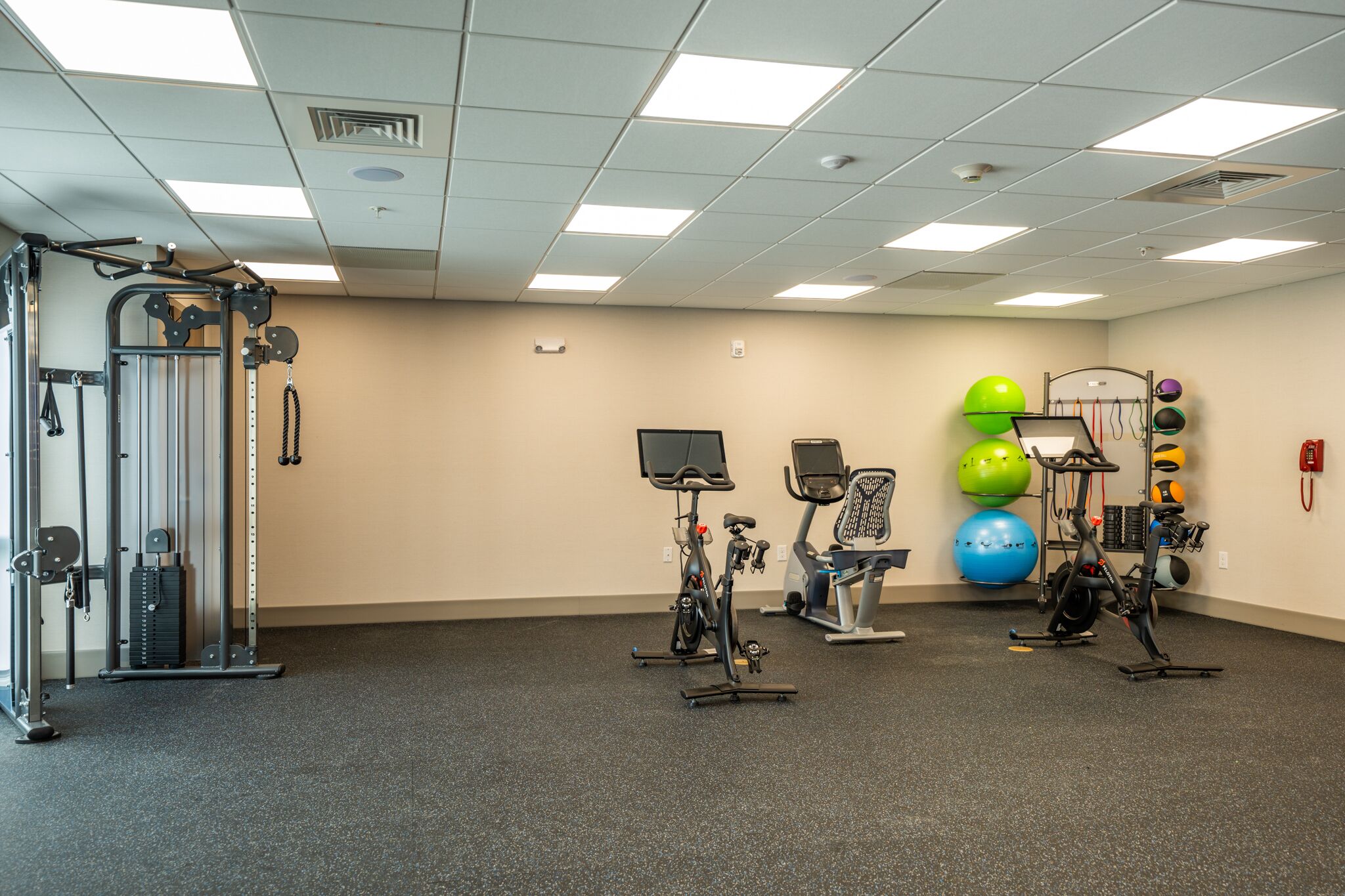A gym with exercise equipment, including treadmills, stationary bikes, and a weight machine.