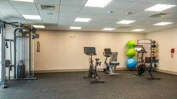 A gym with exercise equipment, including treadmills, stationary bikes, and a weight machine.