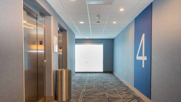 A hallway with an elevator, a trash can, and a large door with the number 4.