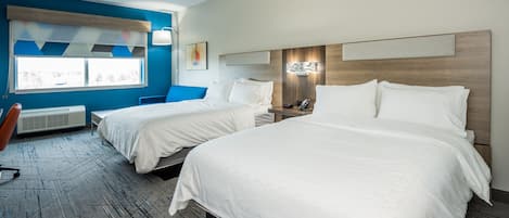 Habitación de hotel con dos camas, un escritorio y una silla. Se ve un ventanal con vistas al exterior.