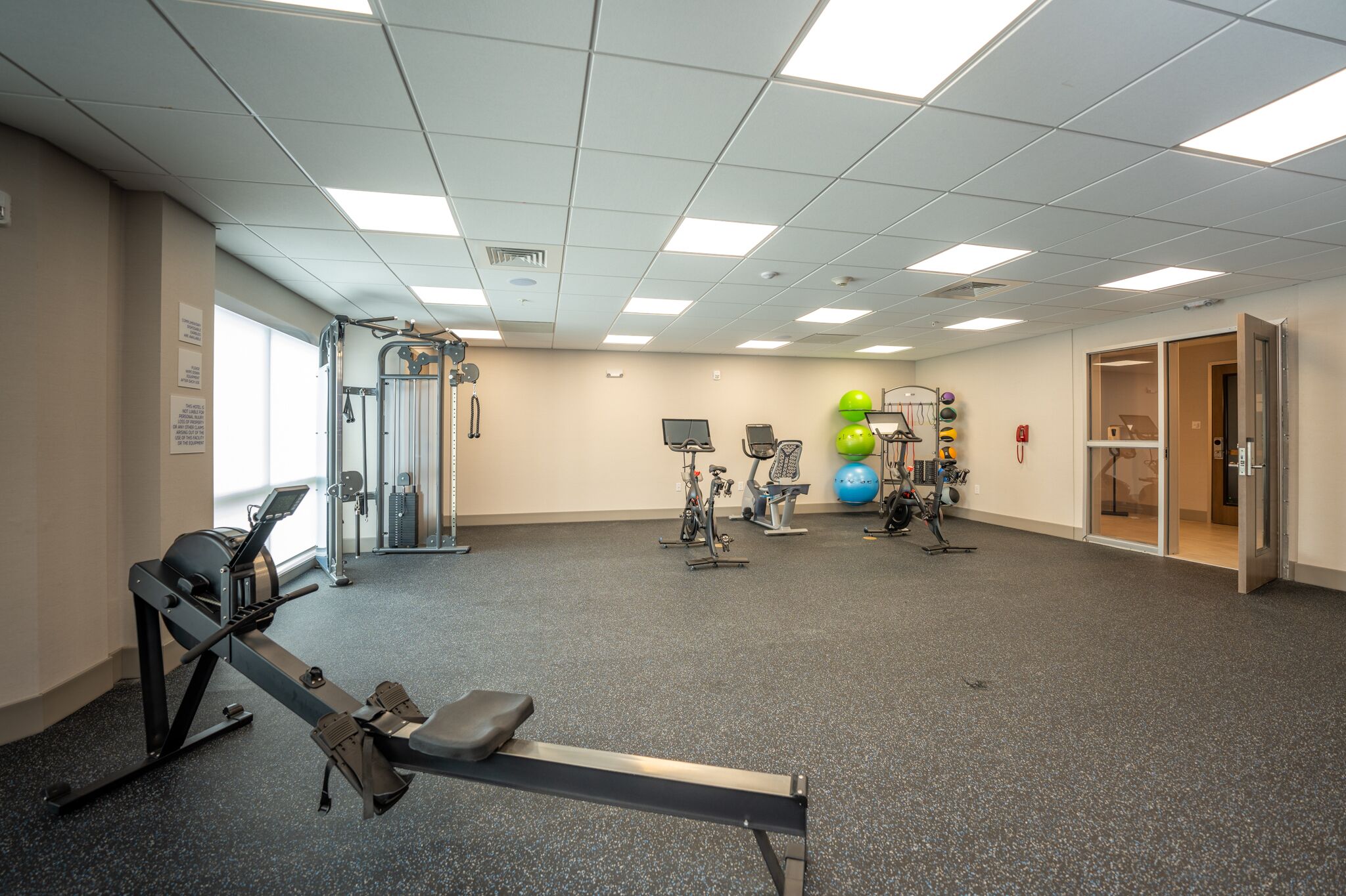 Un gimnasio con máquinas de cardio, equipo de entrenamiento con pesas y pelotas de ejercicio.