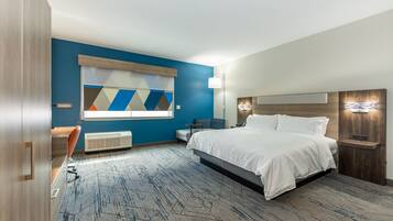 A modern hotel room with a large bed, a desk, and a chair. There is a window with a view of the outside.