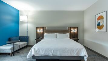 A hotel room with a large bed, a sofa, a small table, and a wall-mounted lamp.