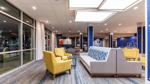 Un hall d’entrée moderne, doté d’espaces aménagés avec des sièges, de grandes fenêtres et d’un mur d’accent bleu.