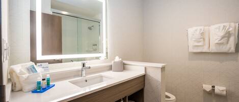 Une salle de bain moderne avec un grand miroir, deux vasques et une douche.