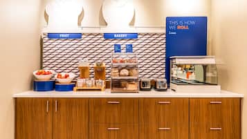 A kitchen counter with labeled sections for fruit and bakery, equipped with various food items and appliances.