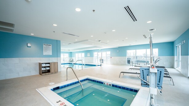 Une piscine intérieure avec des règles d’utilisation clairement affichées, un vestiaire et une vue sur l’espace piscine.