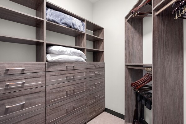 Un vestidor con cajones y estantes de madera, con ropa doblada y una barra para colgar.