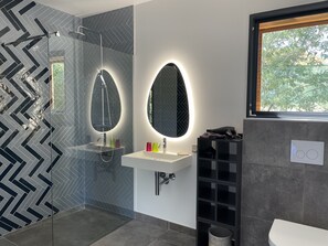 Ein modernes Badezimmer mit Duschkabine aus Glas, Waschtisch mit Spiegel und Toilette.