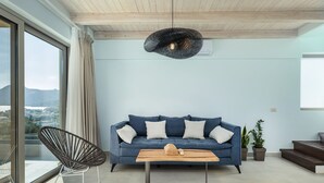 Un salon moderne avec un canapé bleu, un fauteuil en osier, une table basse en bois et un luminaire suspendu.