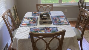 A dining table with a floral table runner, surrounded by wooden chairs. - Buffalo Ny Carols Cape (Bowmansville)