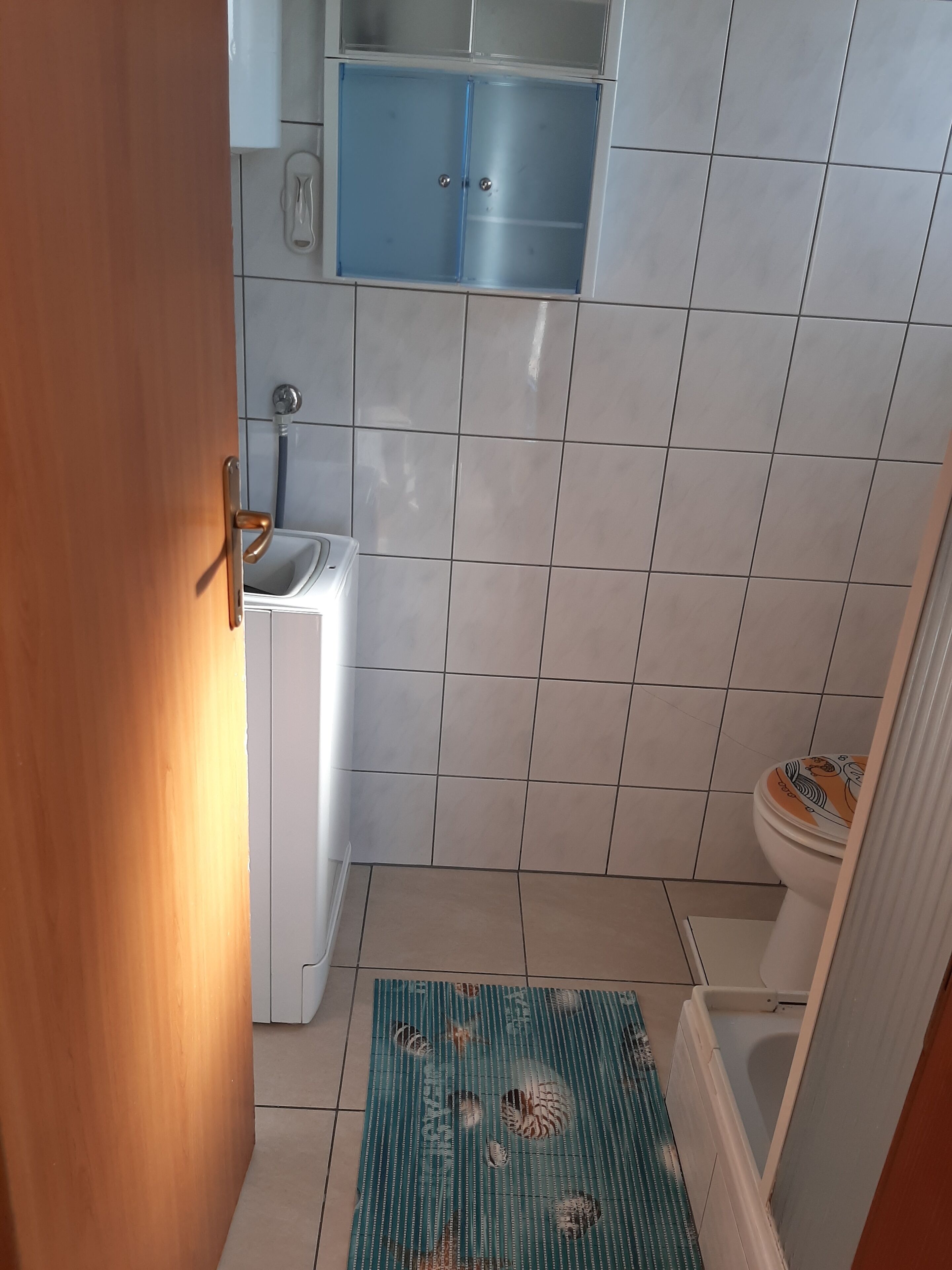 A bathroom with a toilet, sink, and blue cabinet.