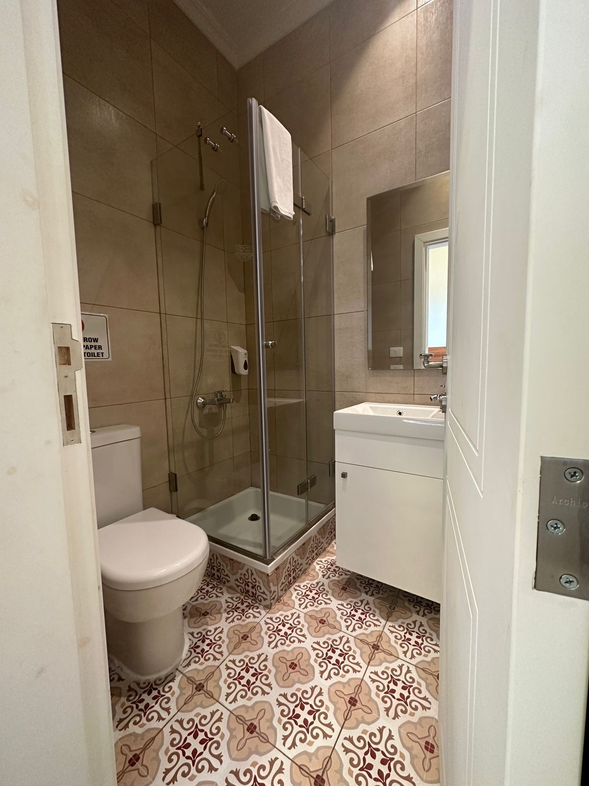Un baño con inodoro, ducha con puerta de cristal y lavabo.