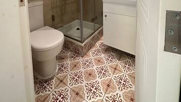 Un baño con inodoro, ducha con puerta de cristal y lavabo.