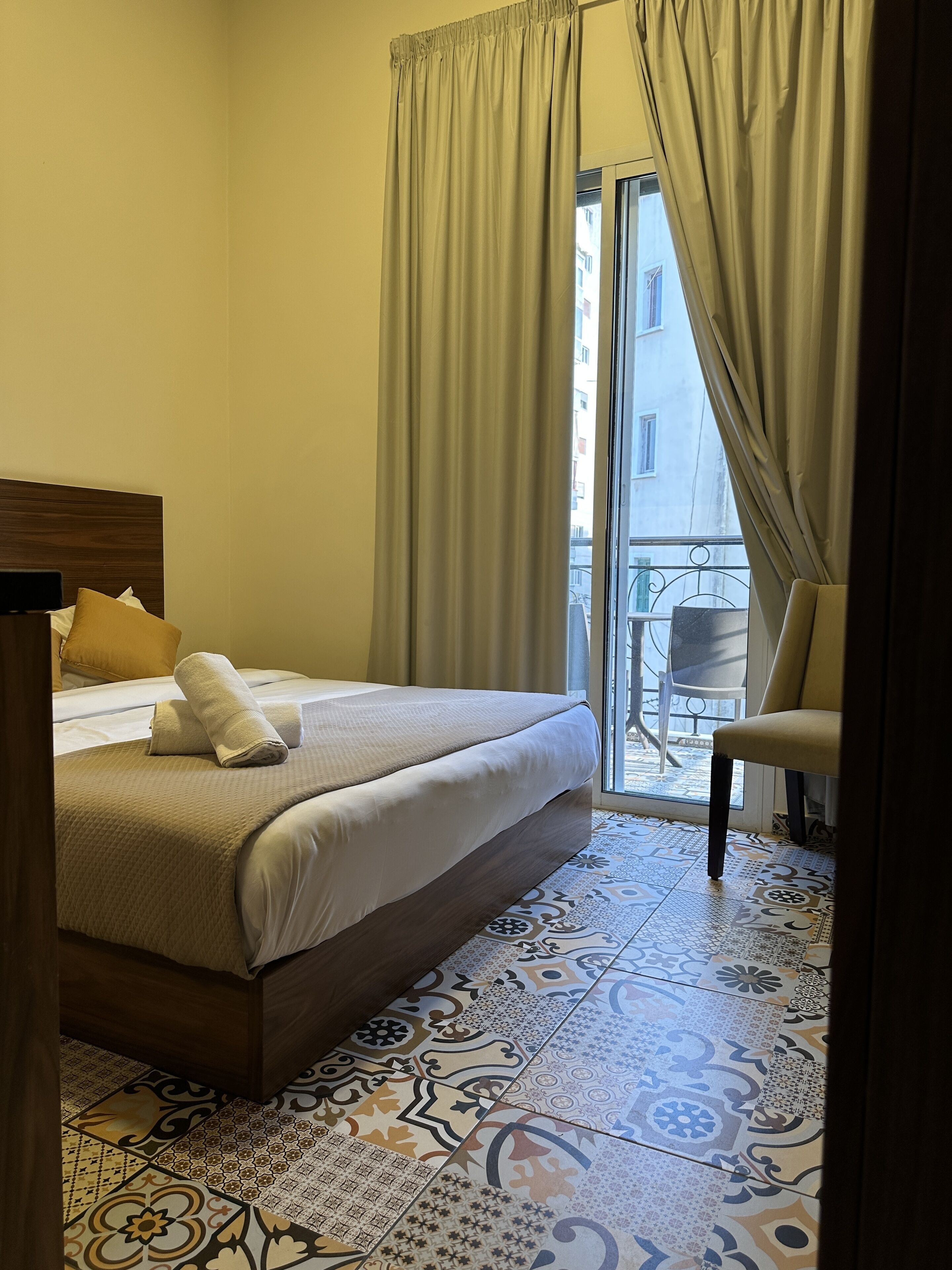 Una habitación de hotel con una cama, una silla y vistas a un balcón.