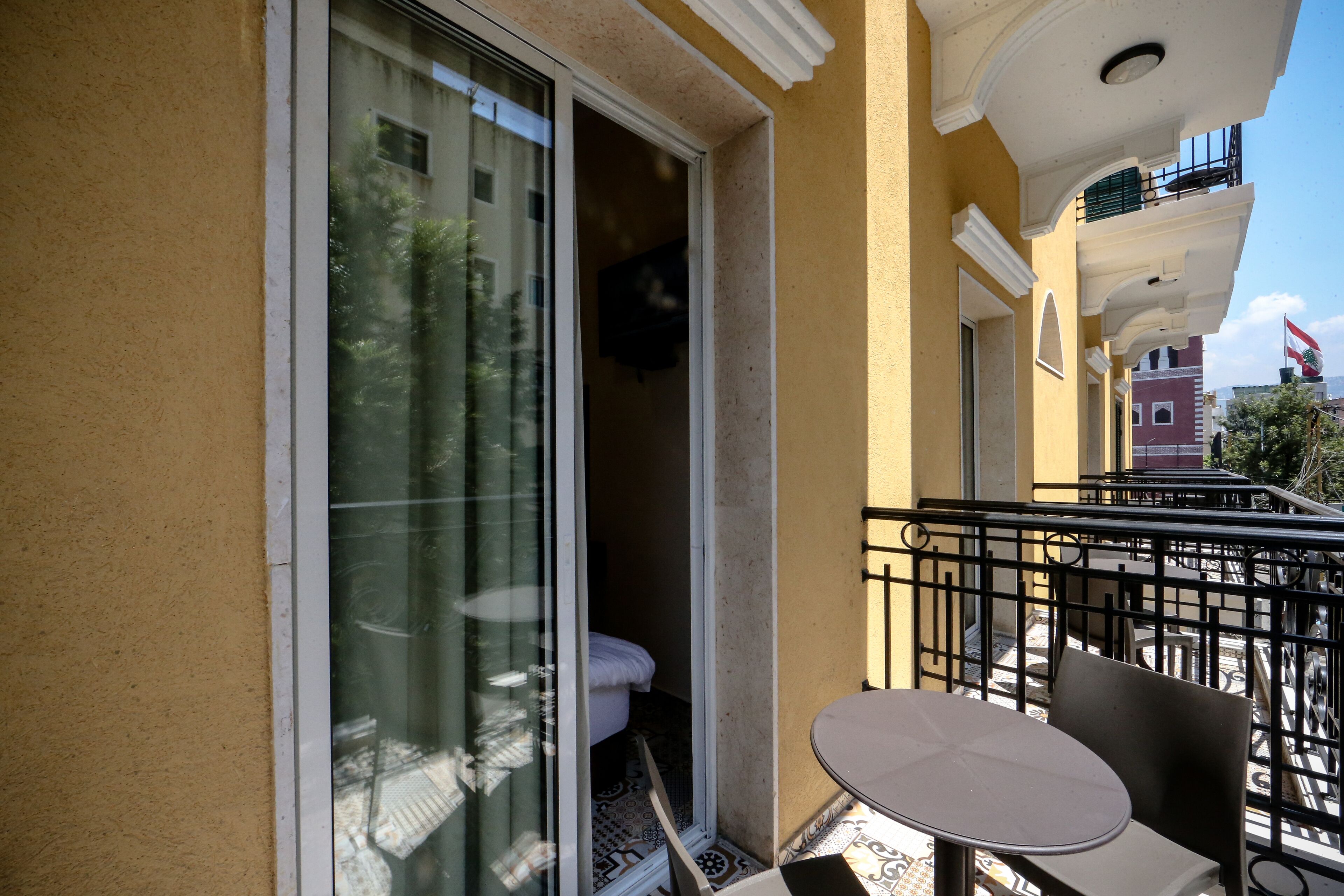 A balcony with a table and chairs, a sliding glass door, and a view of the street.