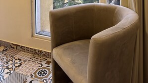 A room with a beige armchair near a window with a view of trees and a bridge. - Mar Mkhayel Studios (Beirut)