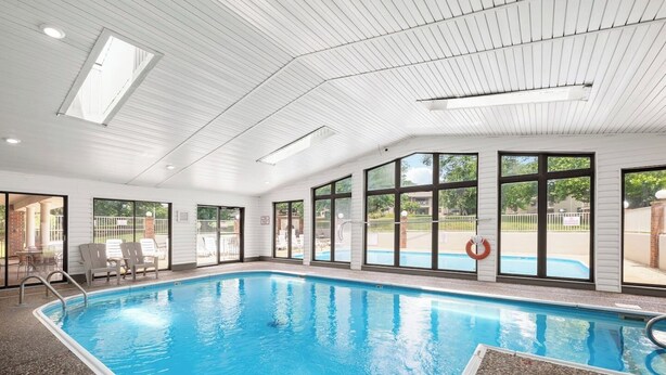 An indoor swimming pool with clear glass walls, a tiled floor, and a lifebuoy by the pool. - Spacious 2BR/2BA – Ground Level, Near Attractions (Branson)