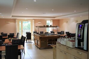 A restaurant with a buffet setup, tables, chairs, and a refrigerator. - Logis L'hôtel Restaurant Verrières (Verrieres-le-Buisson)