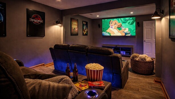 A home theater room with a large screen, reclining seats, popcorn, and a cozy atmosphere.