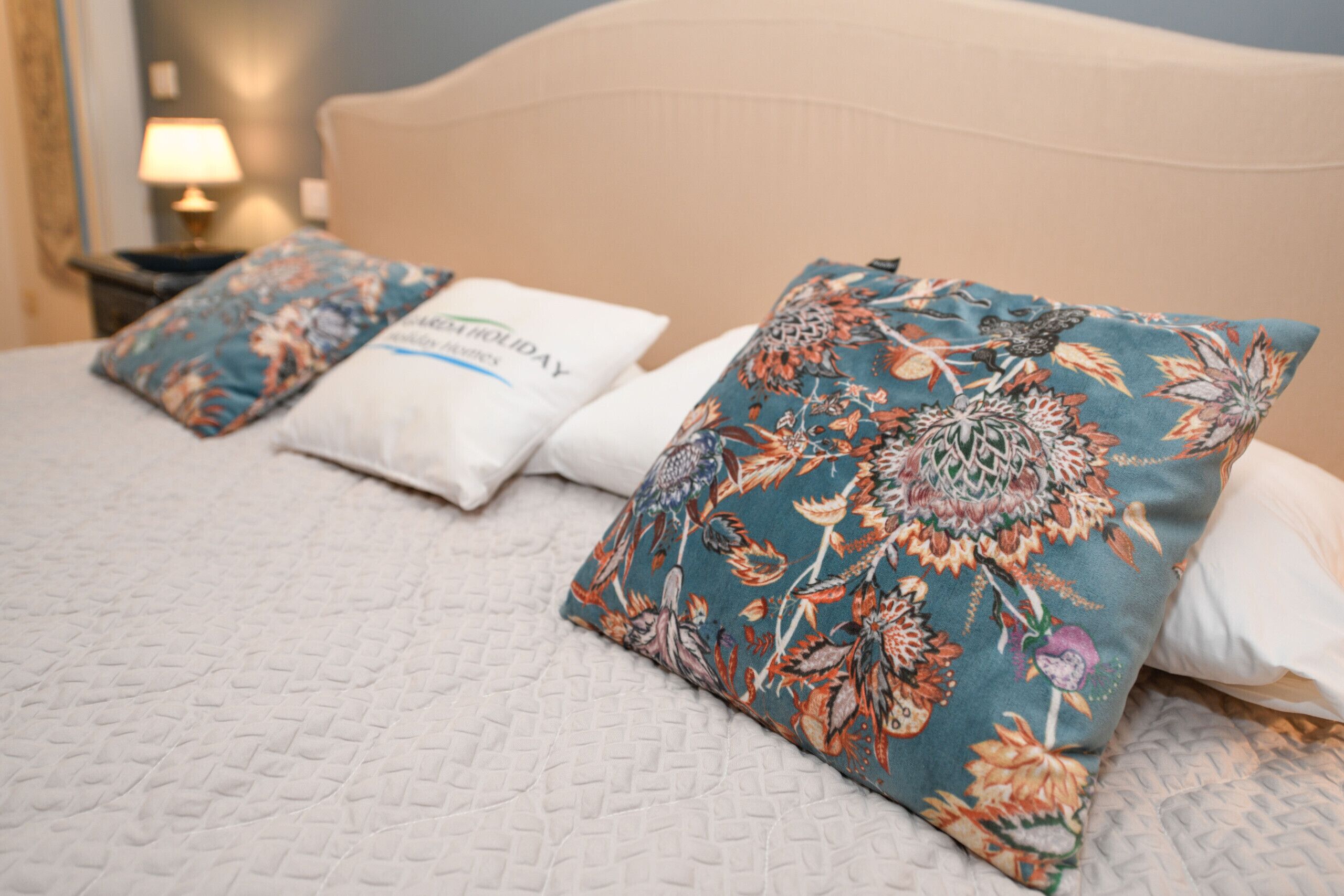 Ein Bett mit blumigen Kissen und einem weißen Kopfkissen mit Text.